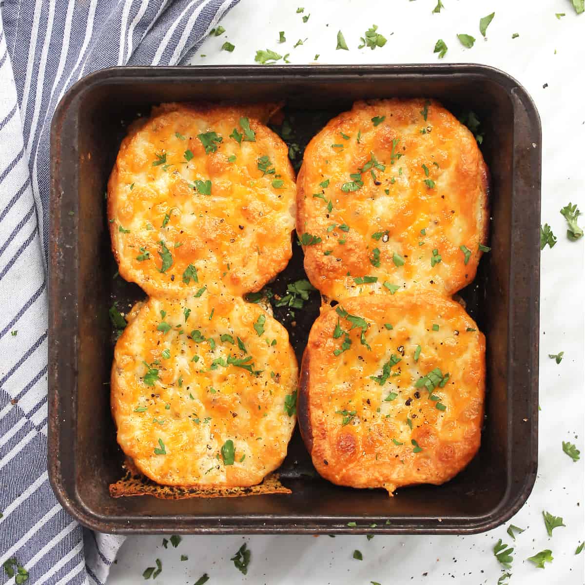 Four pieces of garlic bread in a baking tin garnished with herbs