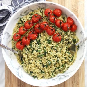 Overhead shot of orzo salad in a bowl topped with roasted tomatoes