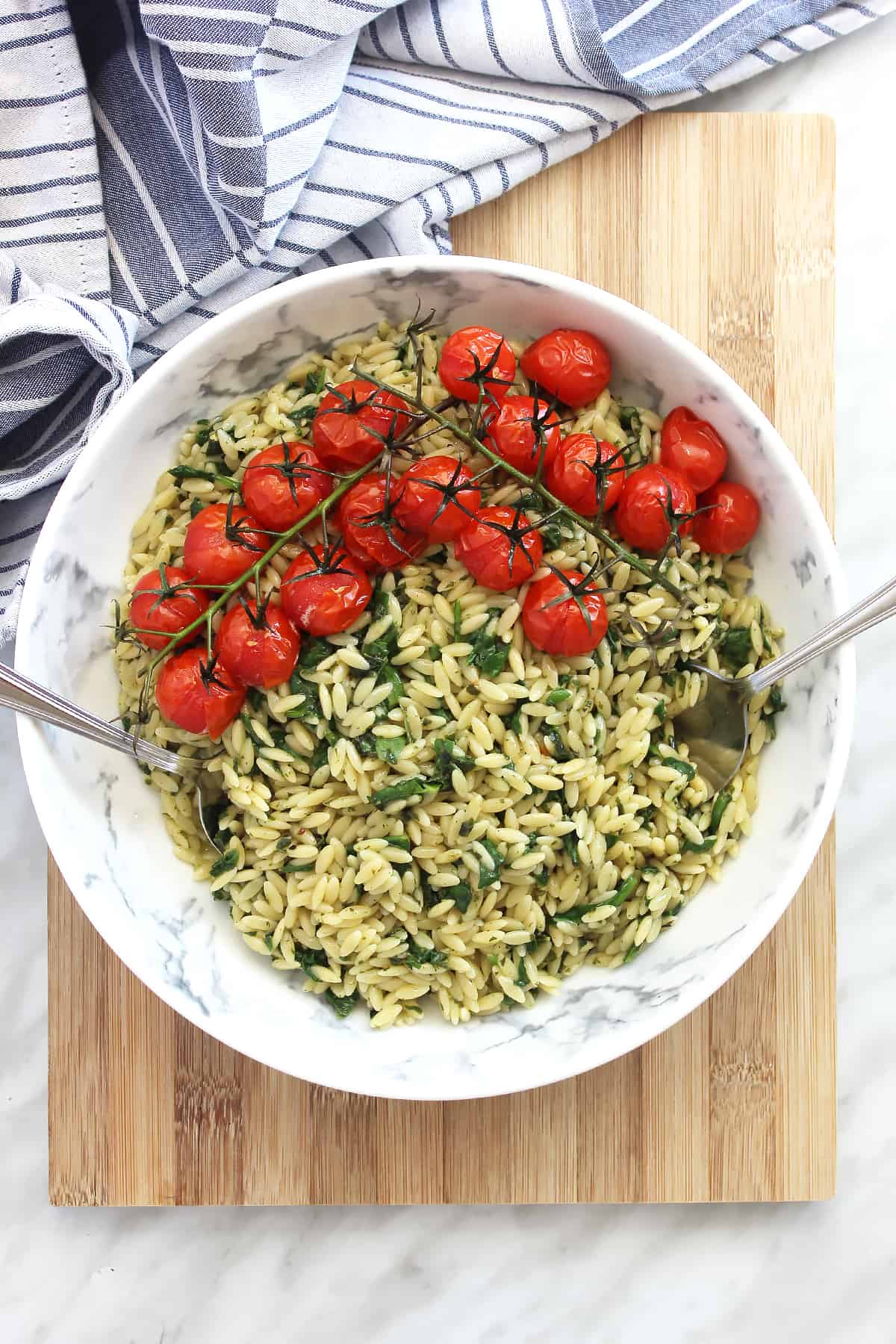 A bowl of orzo pasta salad on a chopping board