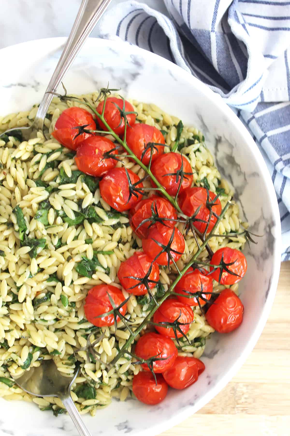 Roasted tomatoes on a bed of spinach orzo salad