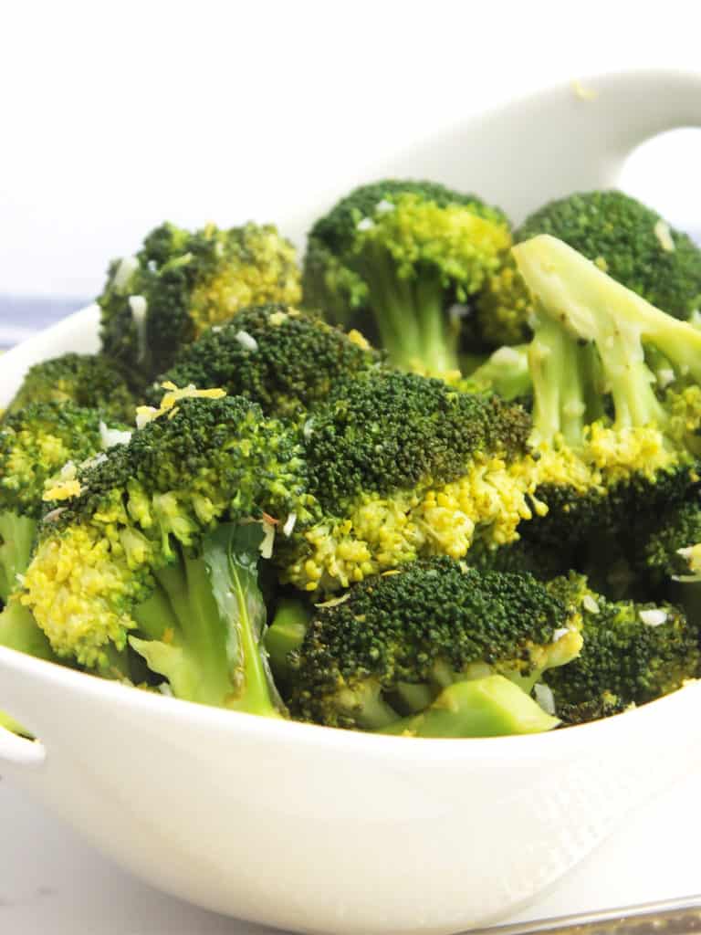 Sautéed broccoli florets in a white serving bowl.