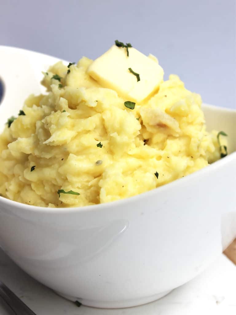 Close up of a pat of butter on top of the mashed potatoes.