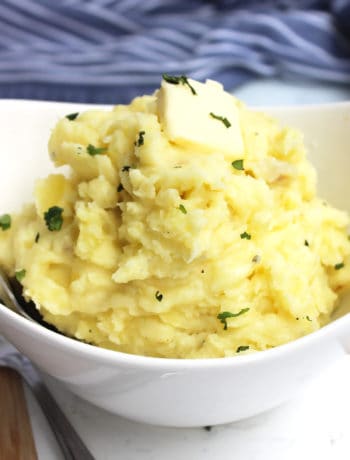 Roasted garlic mashed potato garnished with fresh herbs and butter.