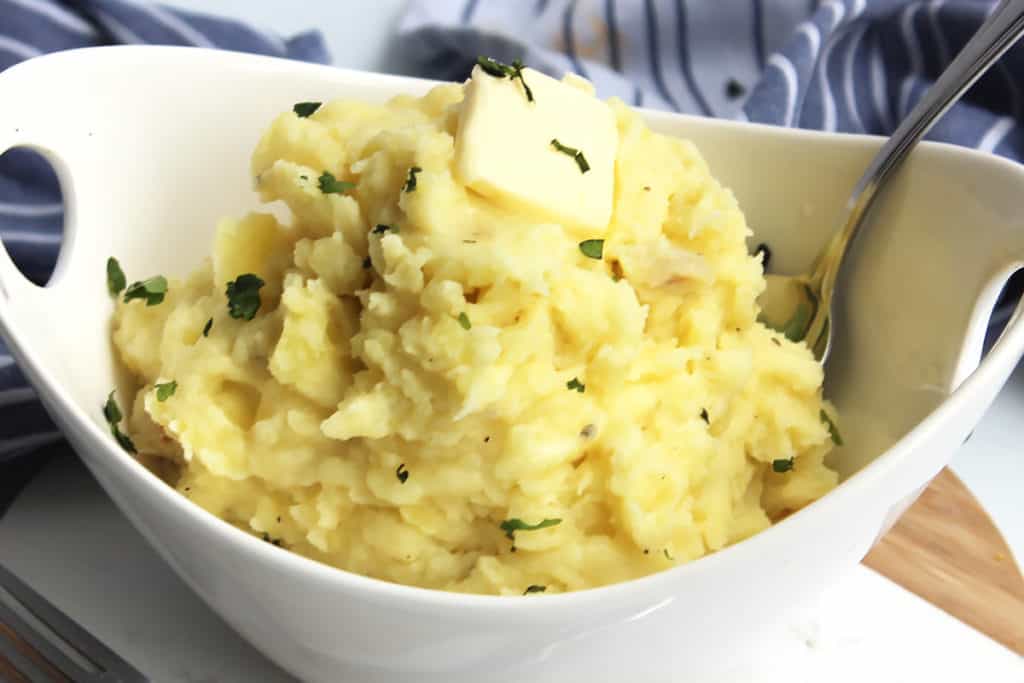Garlic mashed potatoes served in a white bowl with a spoon.