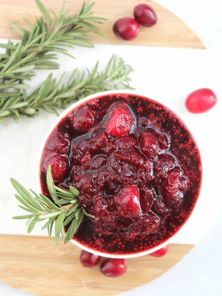 Overhead shot of the cranberry sauce in a small bowl with some fresh rosemary.