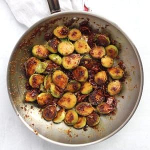 Brussle sprouts in a skillet with bacon and a honey mustard glaze.