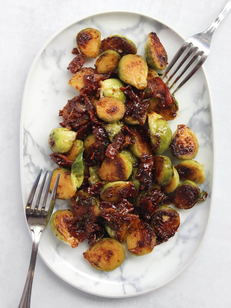 Honey mustard Brussles sprouts on a serving plate with two forks.