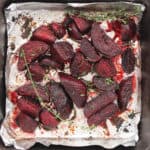 Roasted beet wedges in a baking sheet with fresh thyme.