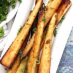 Close up of the glazed parsnips on a white plate.
