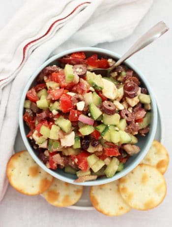 Overhead shot of Greek salsa in a bowl with a spoon next to pita chips.
