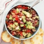 Greek salsa served in a small bowl with pita chips.