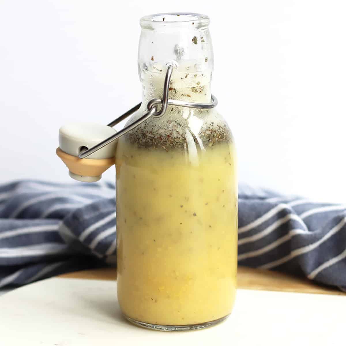 A bottle of the apple cider vinaigrette in front of a blue cloth.