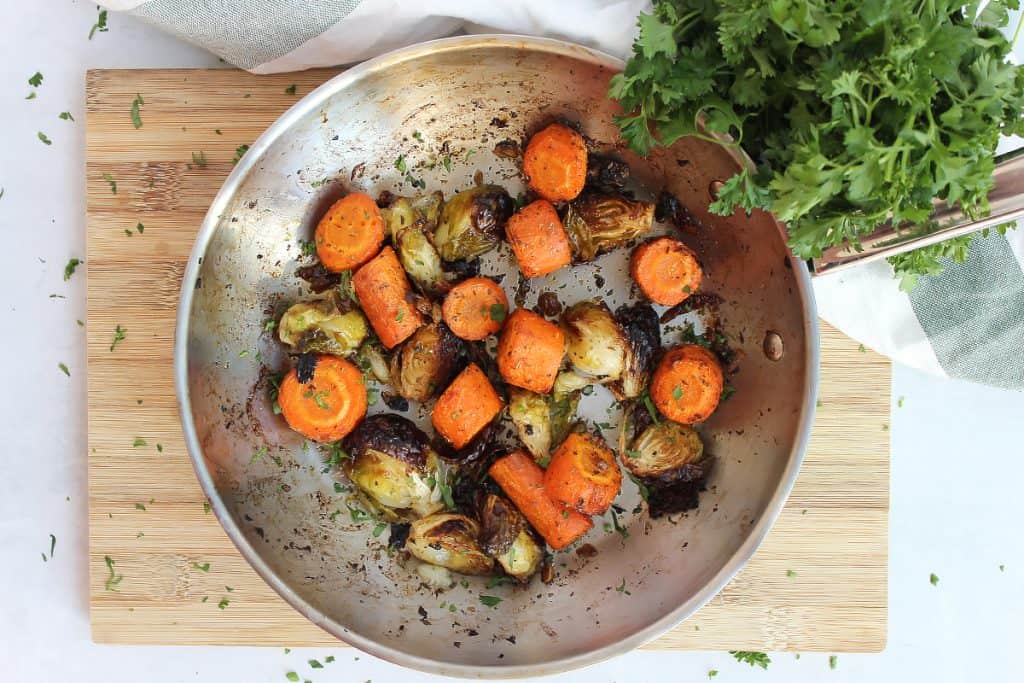 Roasted sprouts and carrots in a silver skillet.