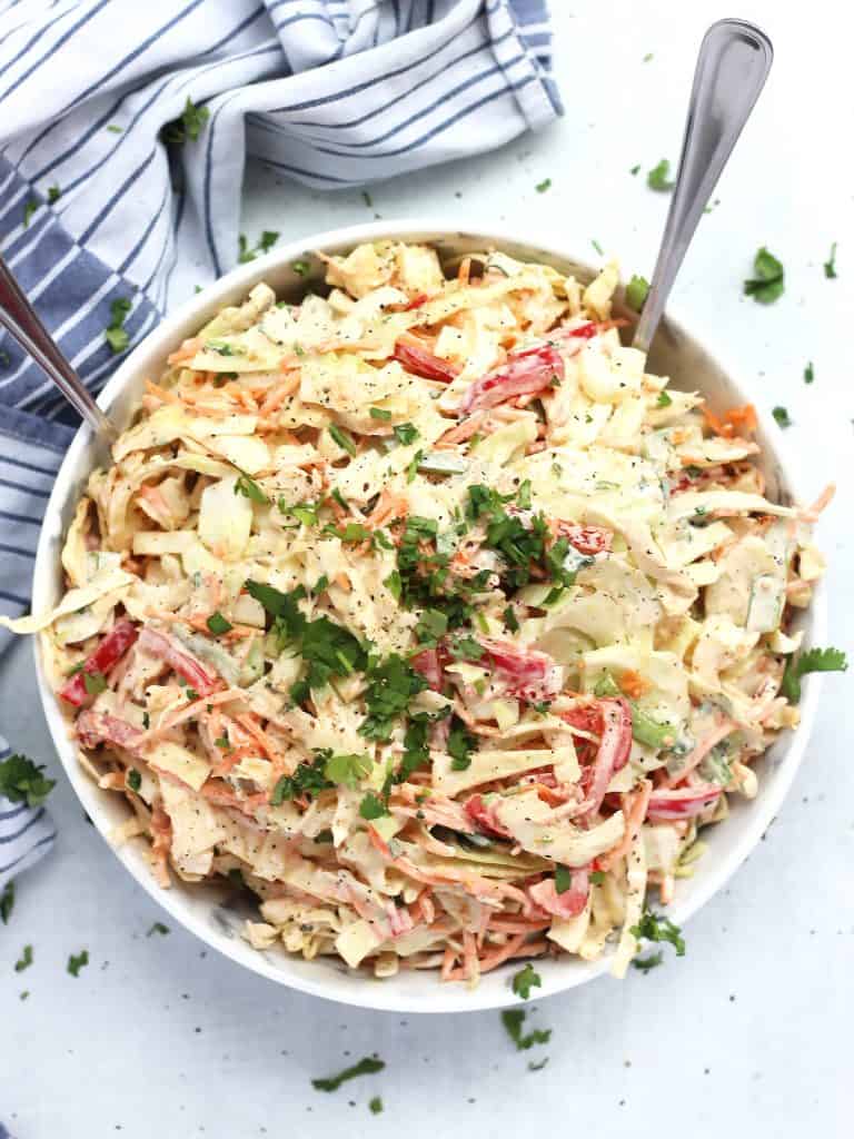 Cajun slaw garnished with fresh cilantro in a large bowl with two serving spoons.