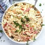 A large bowl of cajun slaw with two serving spoons in it.