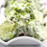 Close up of creamy cilantro cucumber salad on a long serving plate.