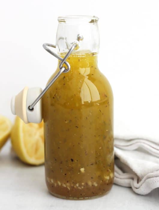 Honey lemon dressing in a glass bottle with a stopper.