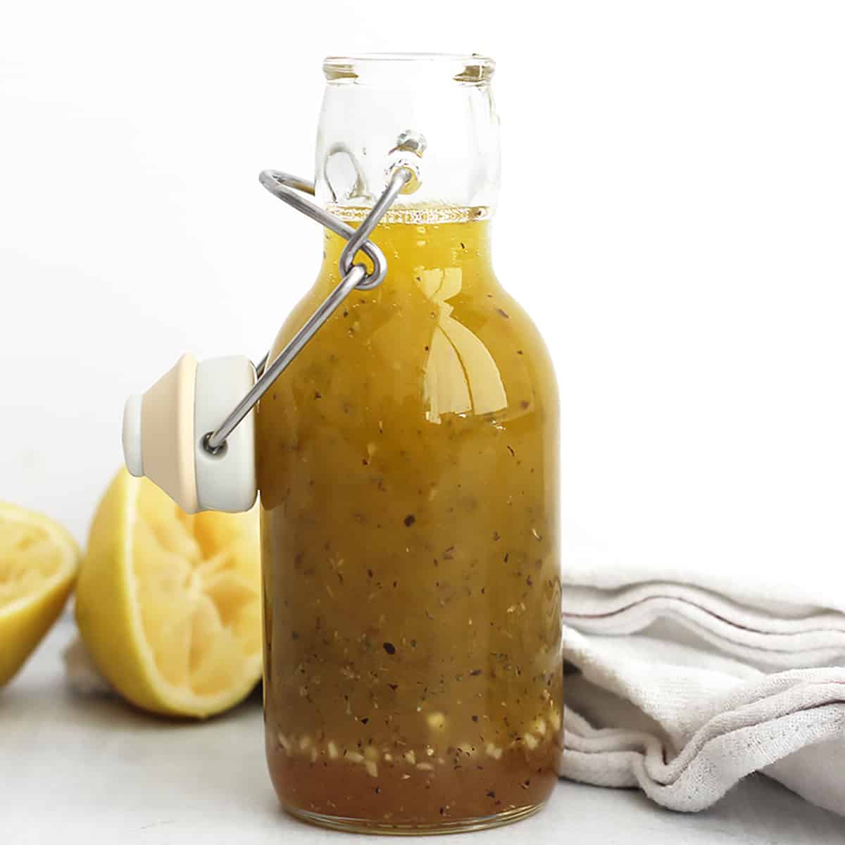 Honey lemon dressing in a sealable glass jar next to squeezed lemon halves.