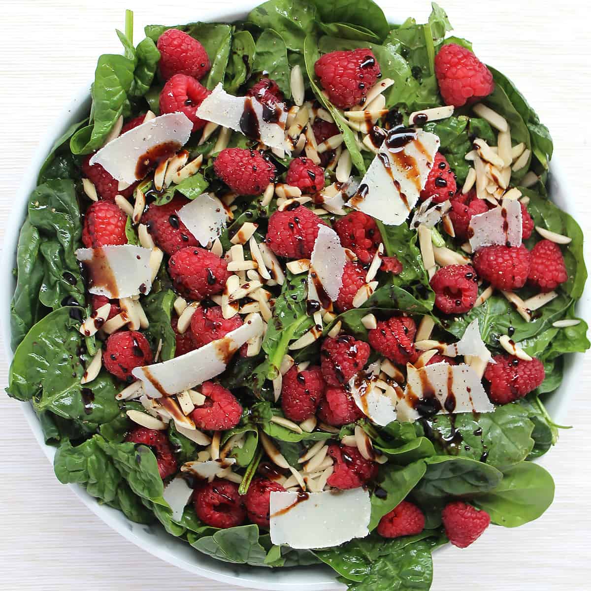 Overhead shot of the spinach raspberry salad with balsamic glaze.