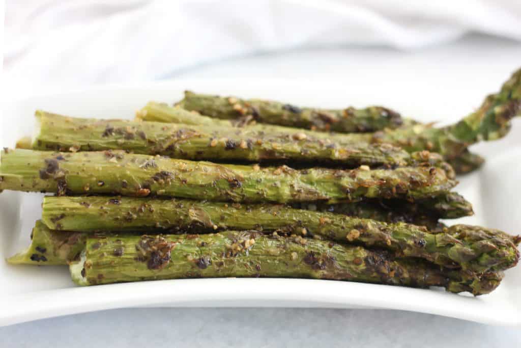 Roasted asparagus on a white serving plate.