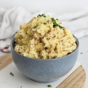 Wholegrain mustard mash in a blue bowl garnished with fresh parsley.