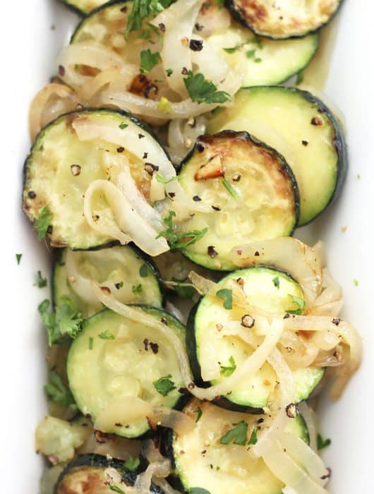 Sautéed zucchini and onions served on a long white plate.