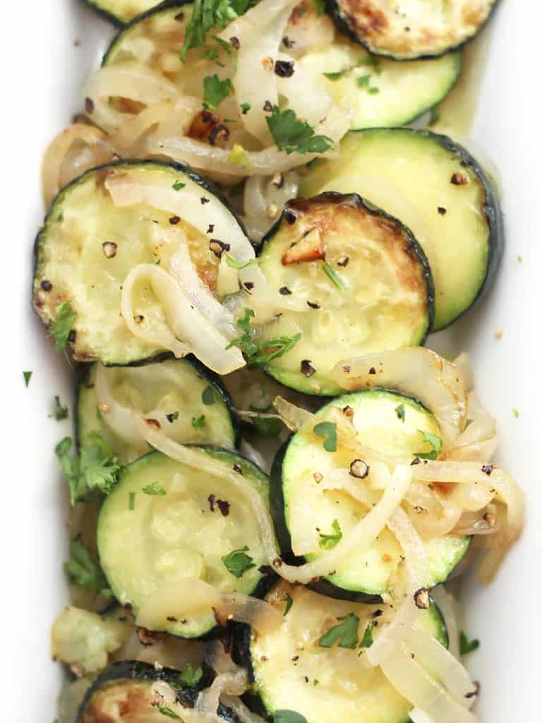 Sautéed zucchini and onions served on a long white plate.