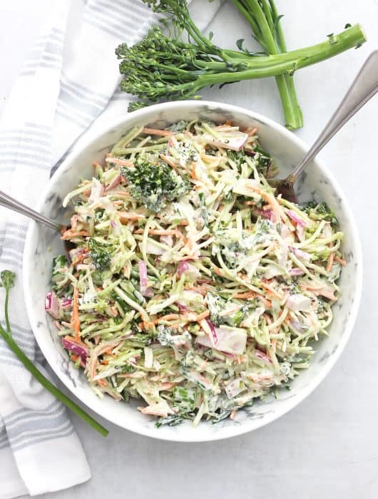 Overhead shot of broccolini slaw in a bowl next to fresh broccolini stems.