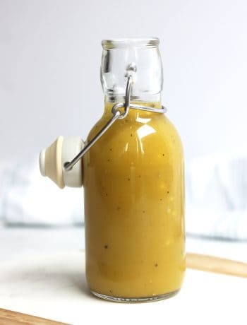 Maple dijon mustard salad dressing in a glass bottle with a stopper.