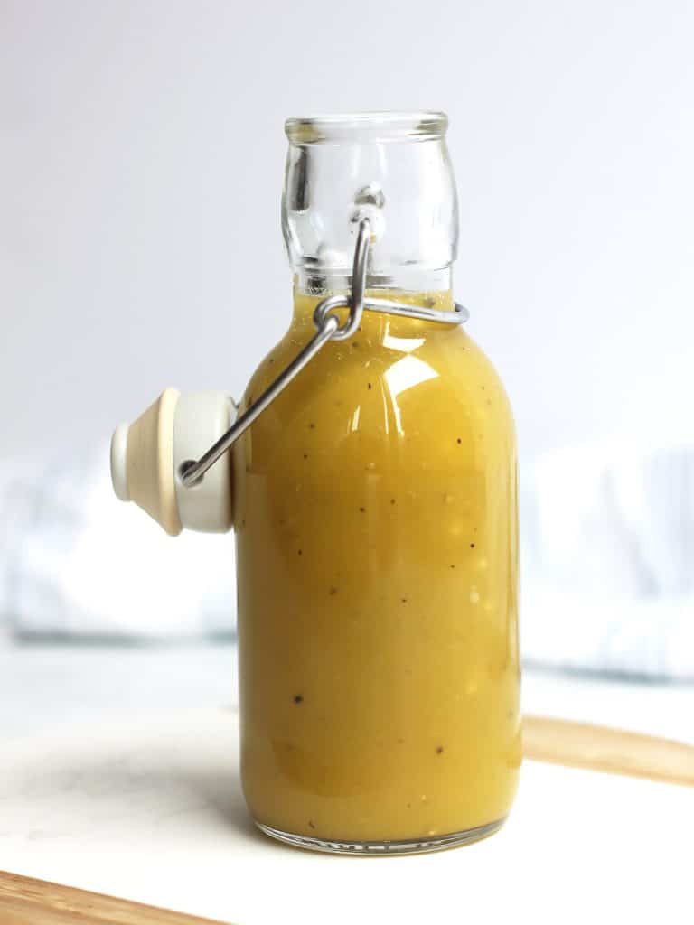 Maple dijon mustard salad dressing in a glass bottle with a stopper.