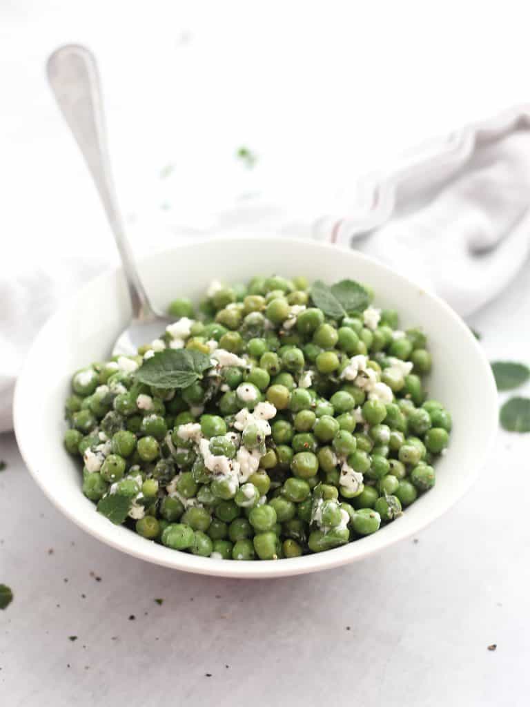 The pea salad served in a white bowl with a spoon.