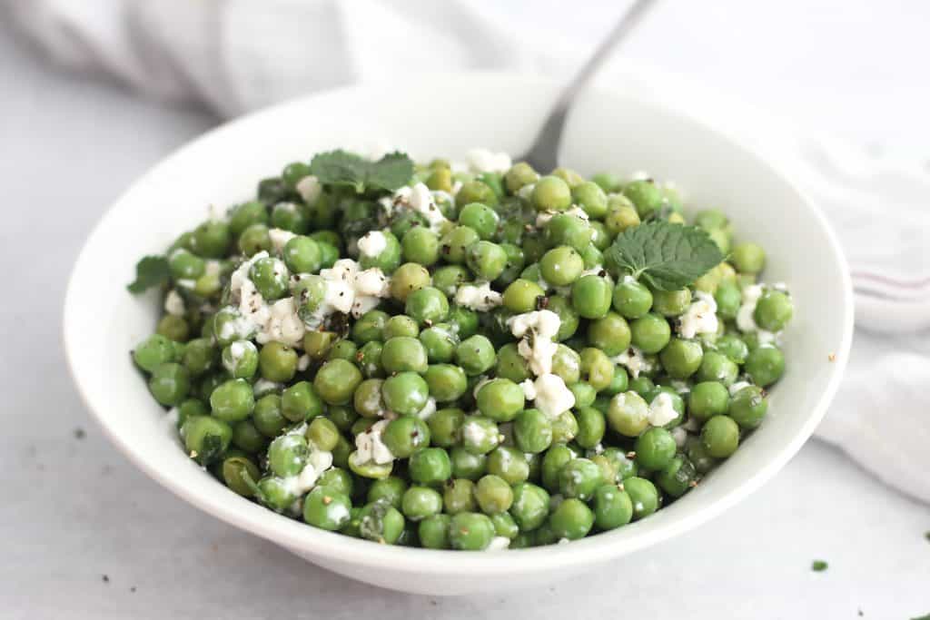 Pea mint and feta salad in a bowl garnished with fresh mint leaves.