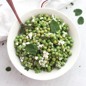 Pea, mint and feta salad in a white bowl with a spoon.