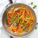 Sautéed peppers and onions in a skillet garnished with fresh parsley.