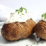 An air fryer hasselback potato topped with sour cream and fresh chives.