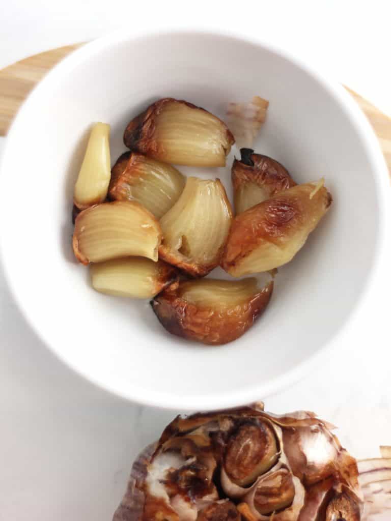 Roasted garlic cloves in a white bowl.