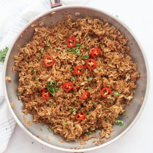 Garlic chili fried rice garnished with fresh sliced chilies and herbs,