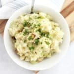 Overhead shot of leeks and mashed potatoes in a white bowl.