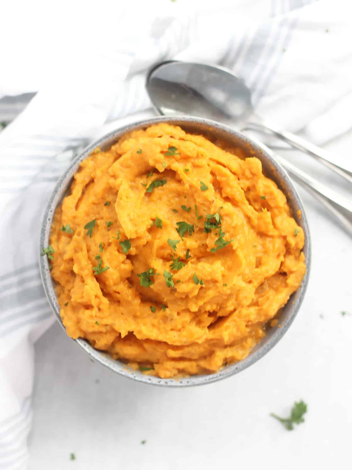 Overhead shot of a bowl of whipped sweet potatoes with two spoons.