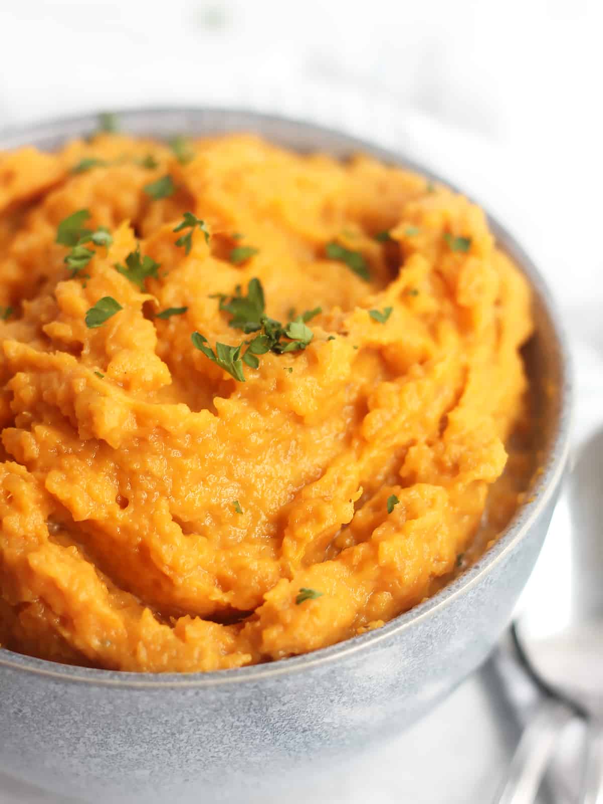 Close up of whipped sweet potatoes garnished with parsley.
