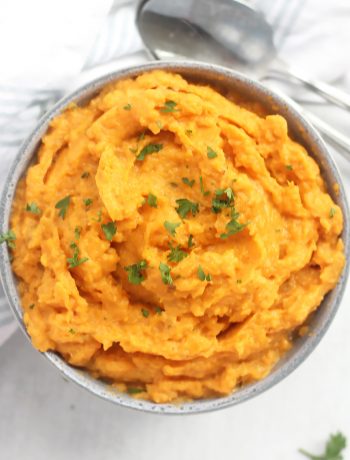Whipped sweet potatoes in a blue bowl with fresh parsley garnish.