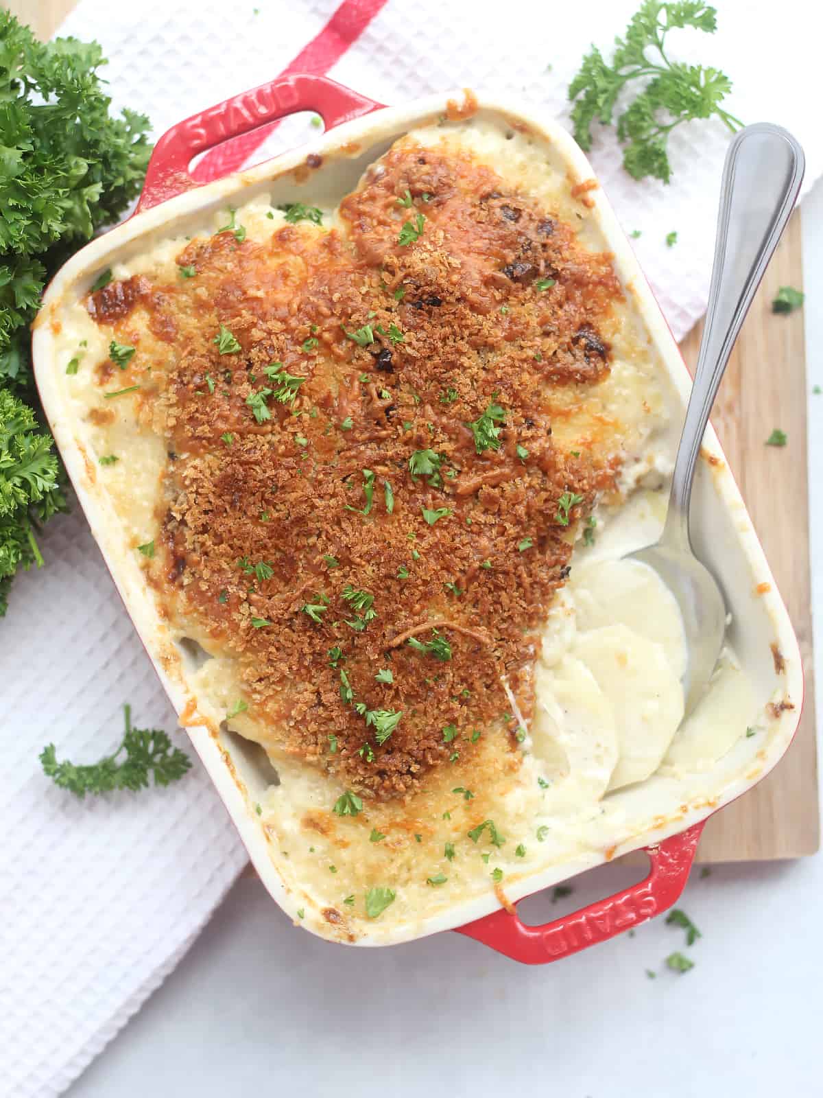 Overhead shot of air fryer potato gratin in a baking dish with some served already with a spoon.