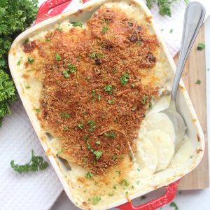 Air fryer gratin with some served and a spoon in the casserole dish.