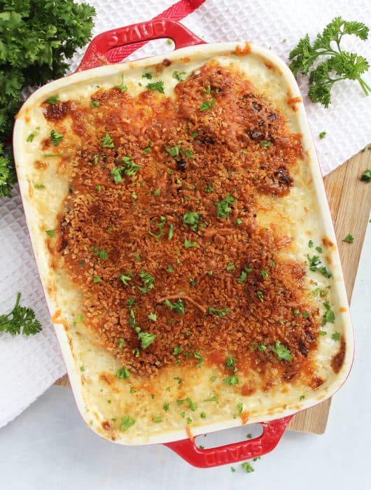 Air fryer potato gratin in a red baking dish garnished with fresh herbs.