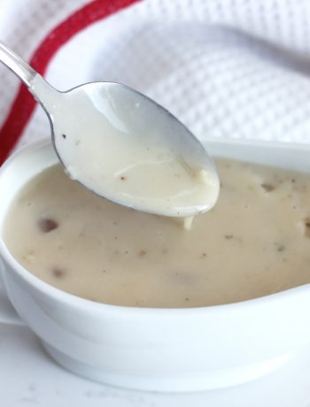 A spoon with gravy dripping off of it.