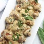 Close up of creamy mushrooms topped with fresh basil.