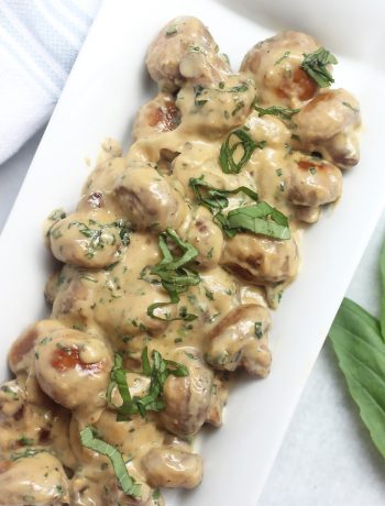 Overhead shot of creamy basil mushrooms on a white serving plate.