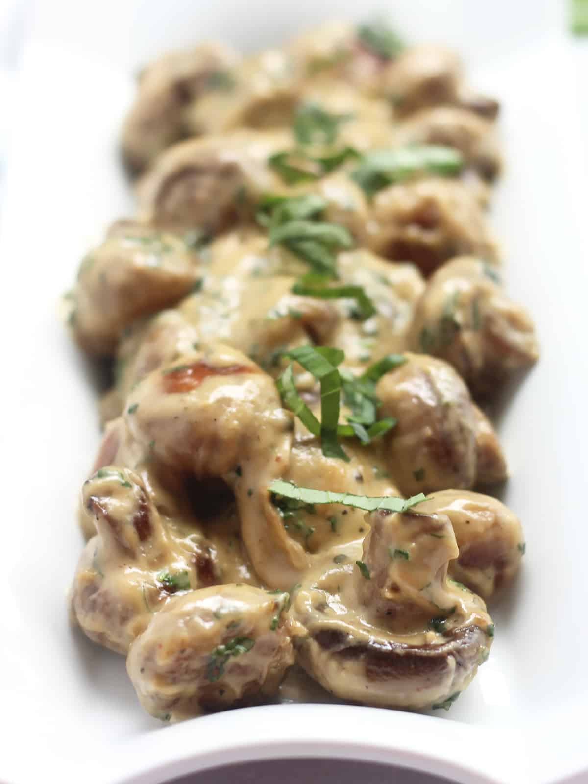 Baby mushrooms coated in cream and garnished with fresh basil.