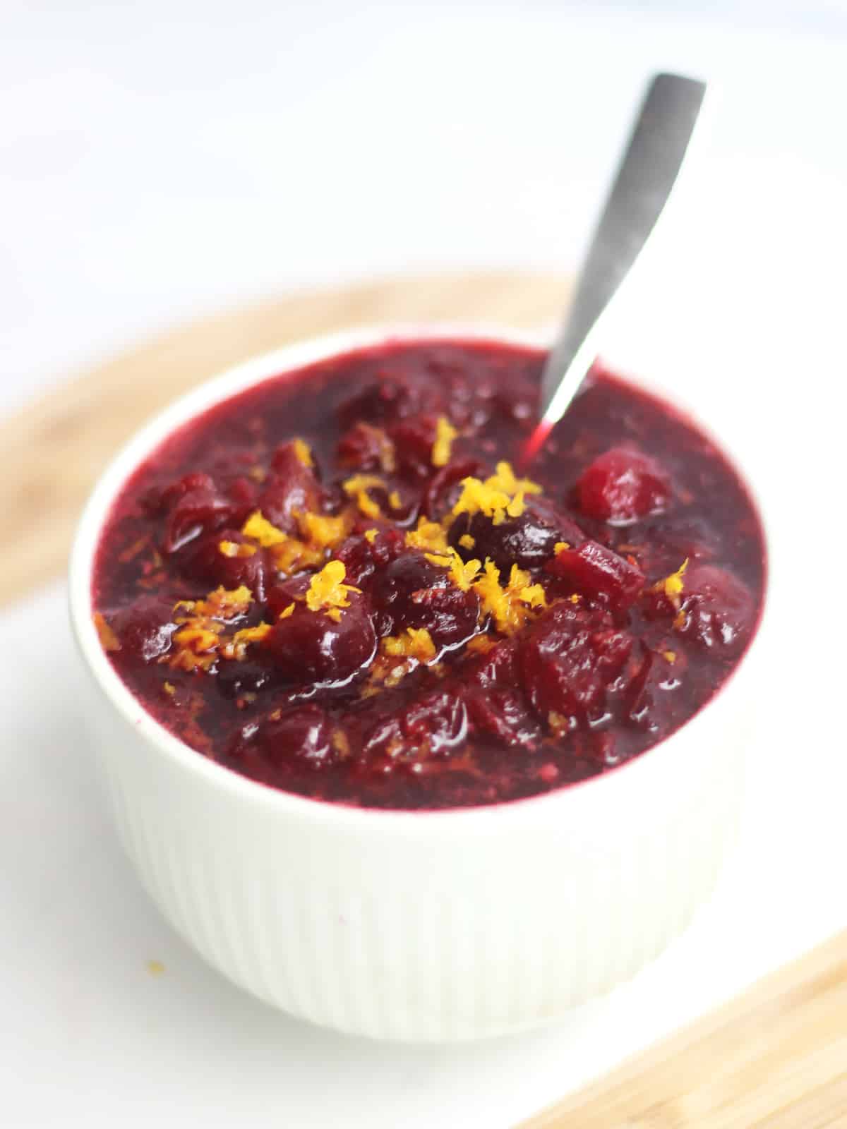 Whiskey cranberry sauce in a small bowl with grated orange zest.