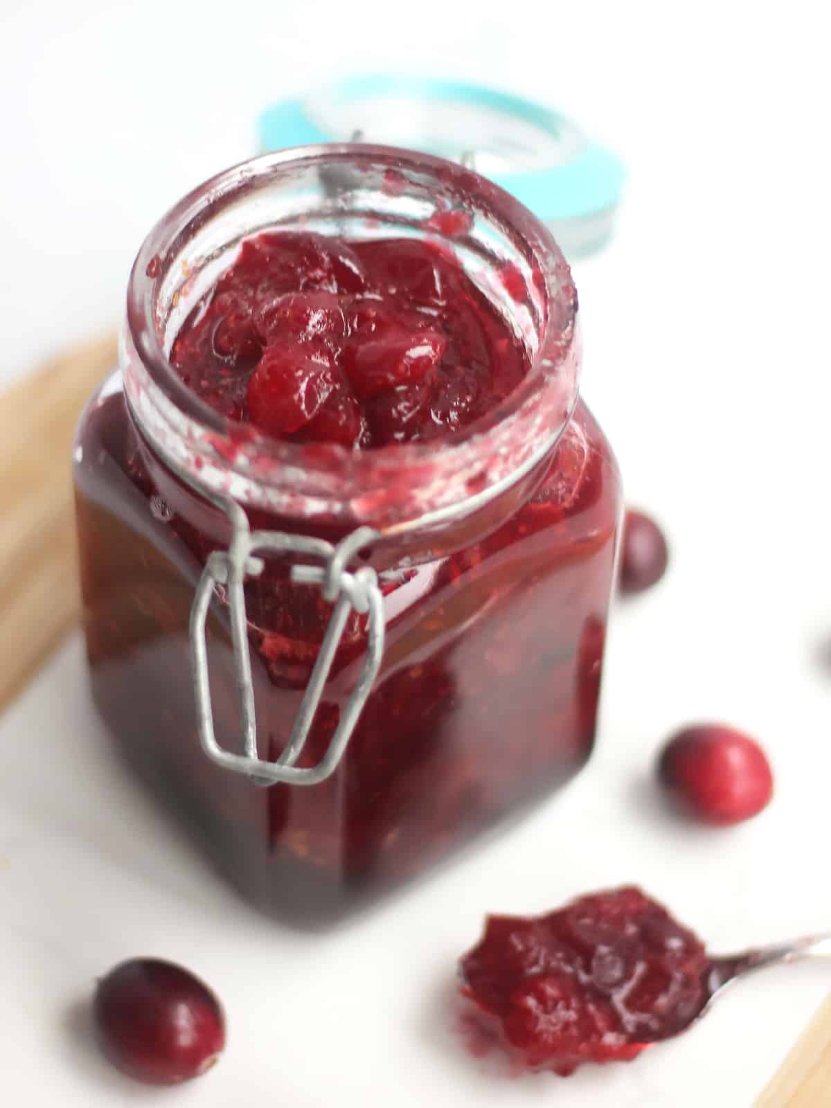 A jar of cranberry sauce next to a spoon.